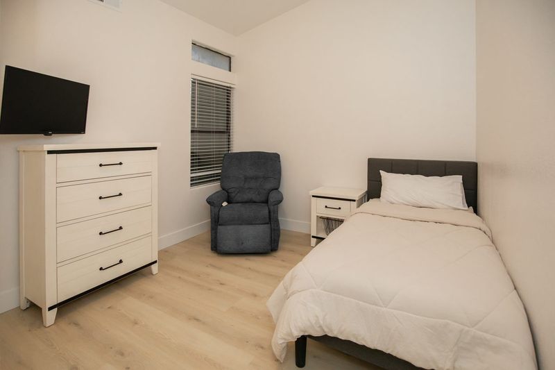 Resident bedroom with television, dresser, and recliner chair