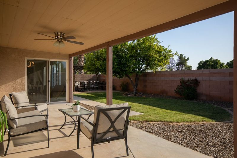 Covered back patio with outdoor seating and a ceiling fan