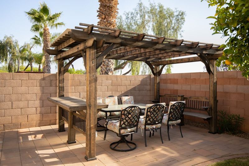 Wooden pergola over a long outdoor dining table in the backyard